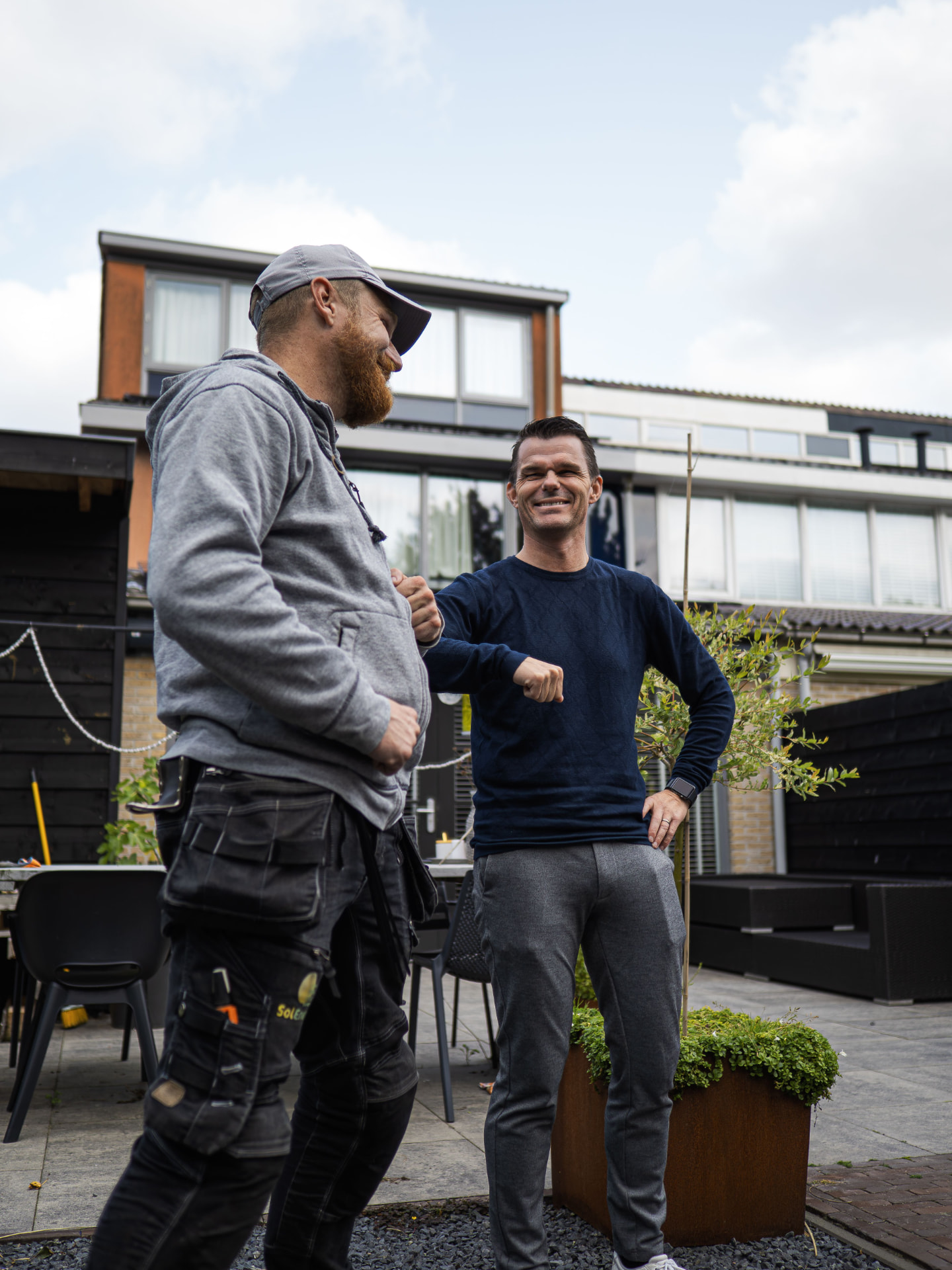 Hantverkare och kund som hälsar varmt utanför ett hus